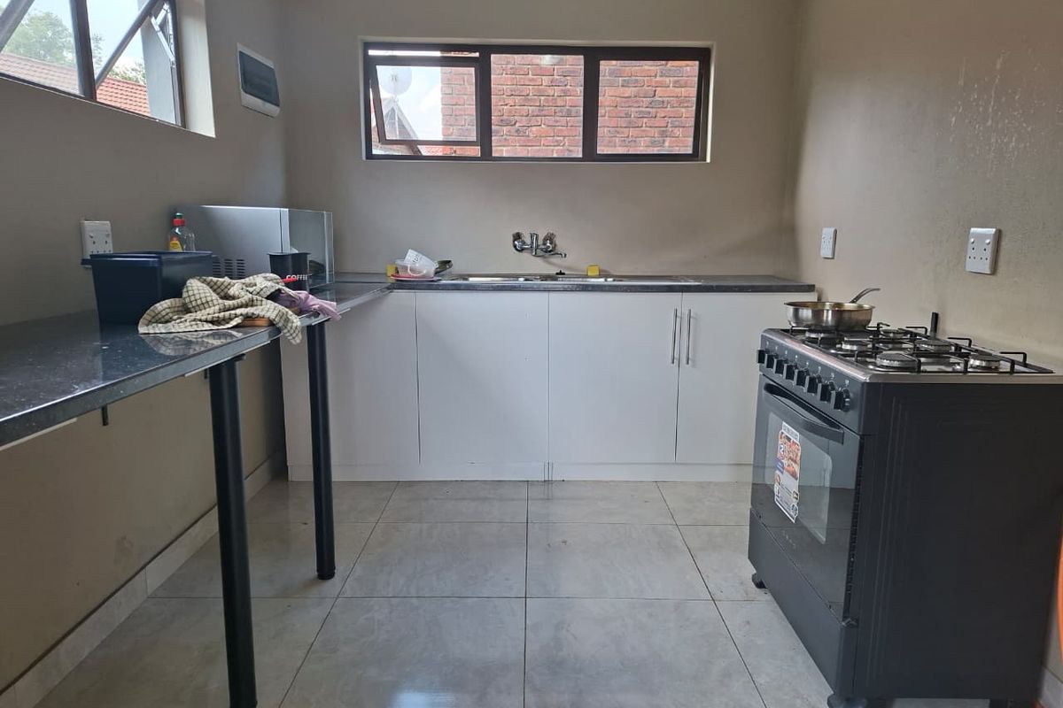 A functional kitchen featuring white cabinetry, dark stone-look countertops, a stainless steel sink, and a freestanding gas stove with oven.