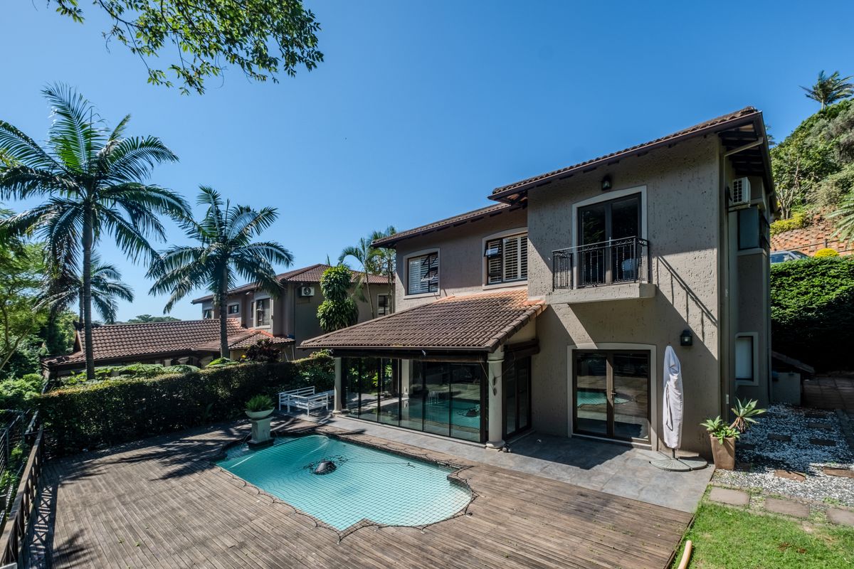Rear view of the townhouse featuring a swimming pool, wooden decking, a private balcony, and well-maintained exterior finishes.