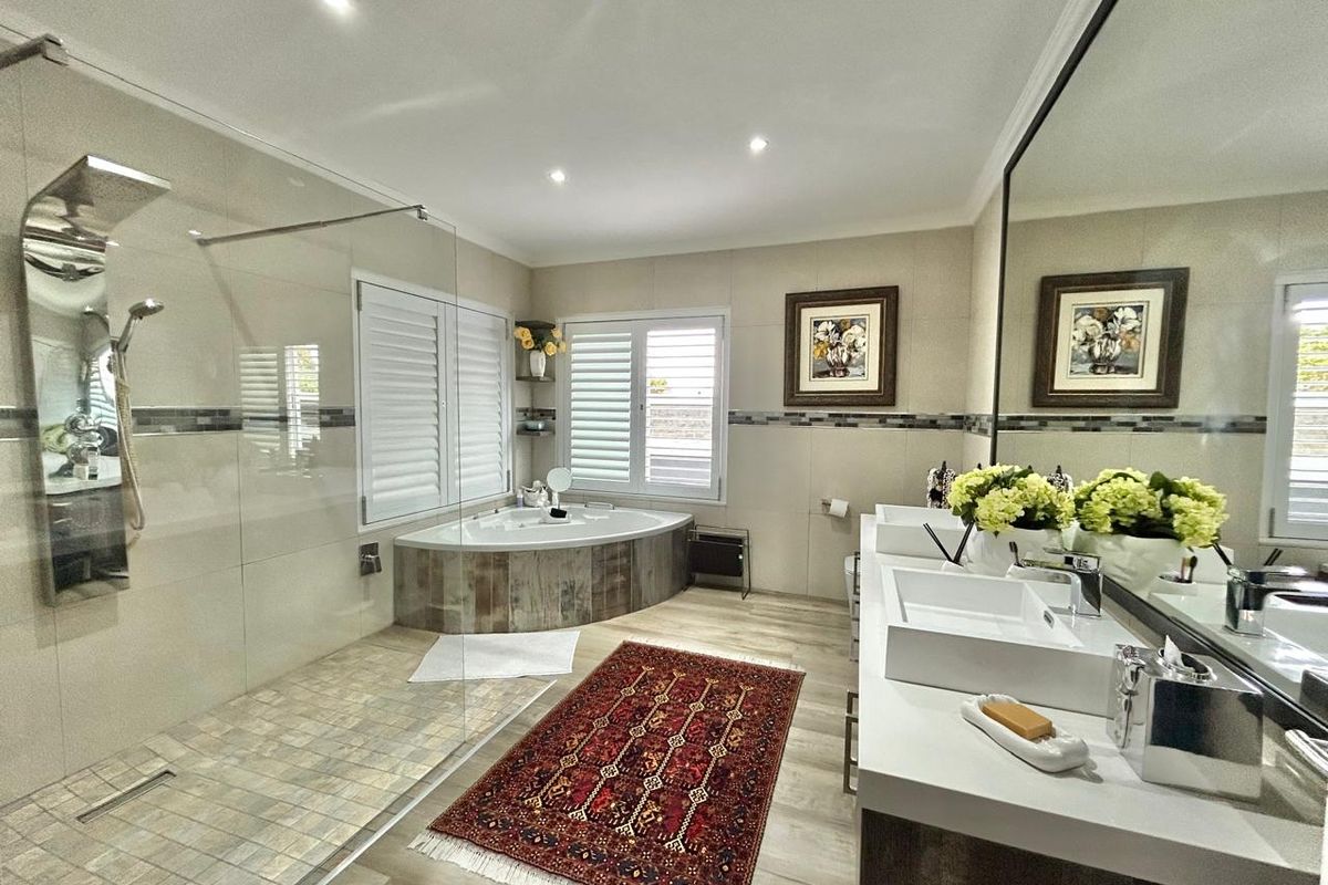 Modern bathroom featuring a large walk-in shower with rainfall showerhead, corner soaking tub, and double vanity with integrated sinks and large wall mirror.