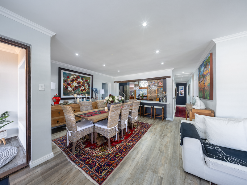 Spacious open-plan dining and living area featuring modern laminate flooring, recessed lighting, and a breakfast bar connecting to the kitchen.