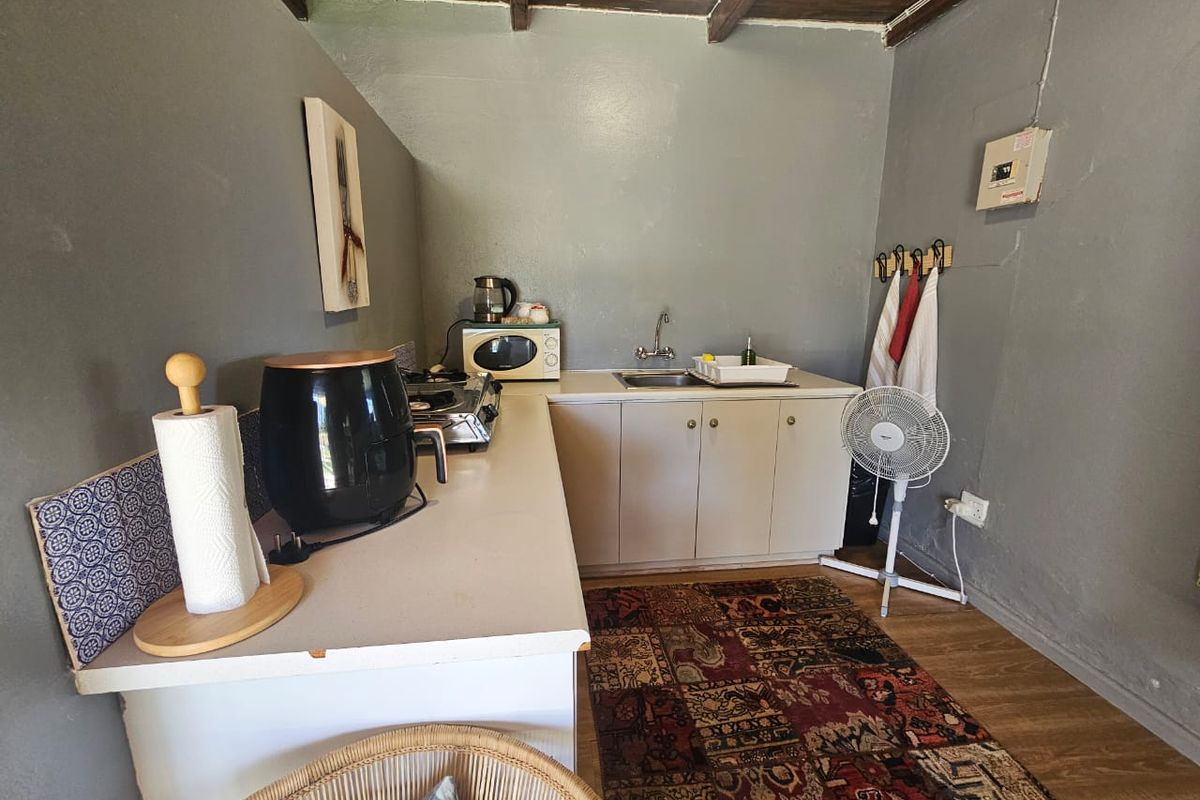 A compact kitchen area featuring basic cabinetry, a stainless steel sink, and exposed timber ceiling beams.
