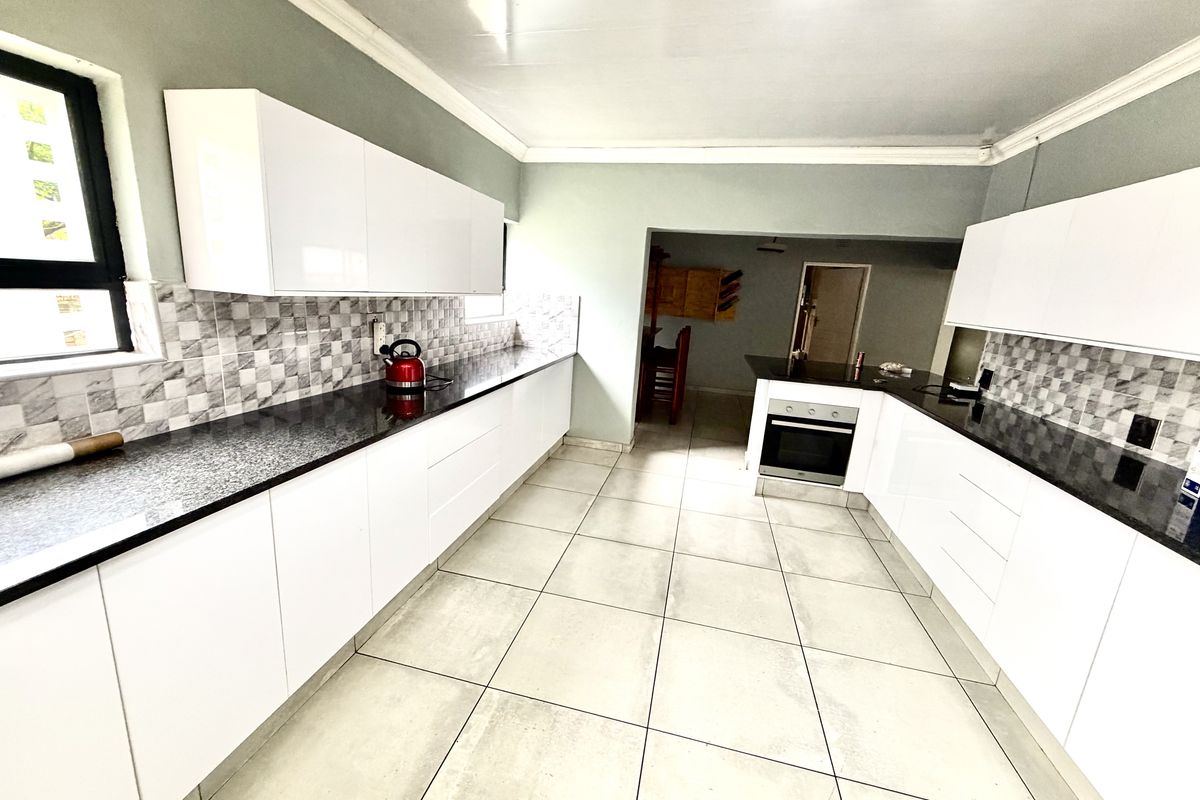 Modern kitchen featuring white cabinetry, contrasting black granite countertops, a tiled backsplash, and built-in oven, offering a clean and functional workspace.