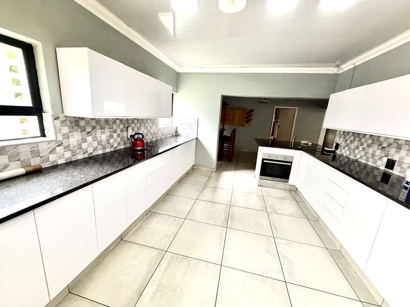 Modern kitchen featuring white cabinetry, contrasting black granite countertops, a tiled backsplash, and built-in oven, offering a clean and functional workspace.