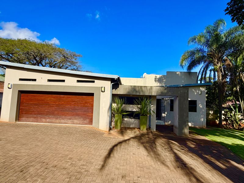 Front elevation of a modern house featuring a paved driveway, double garage with timber door, and a covered entrance area.