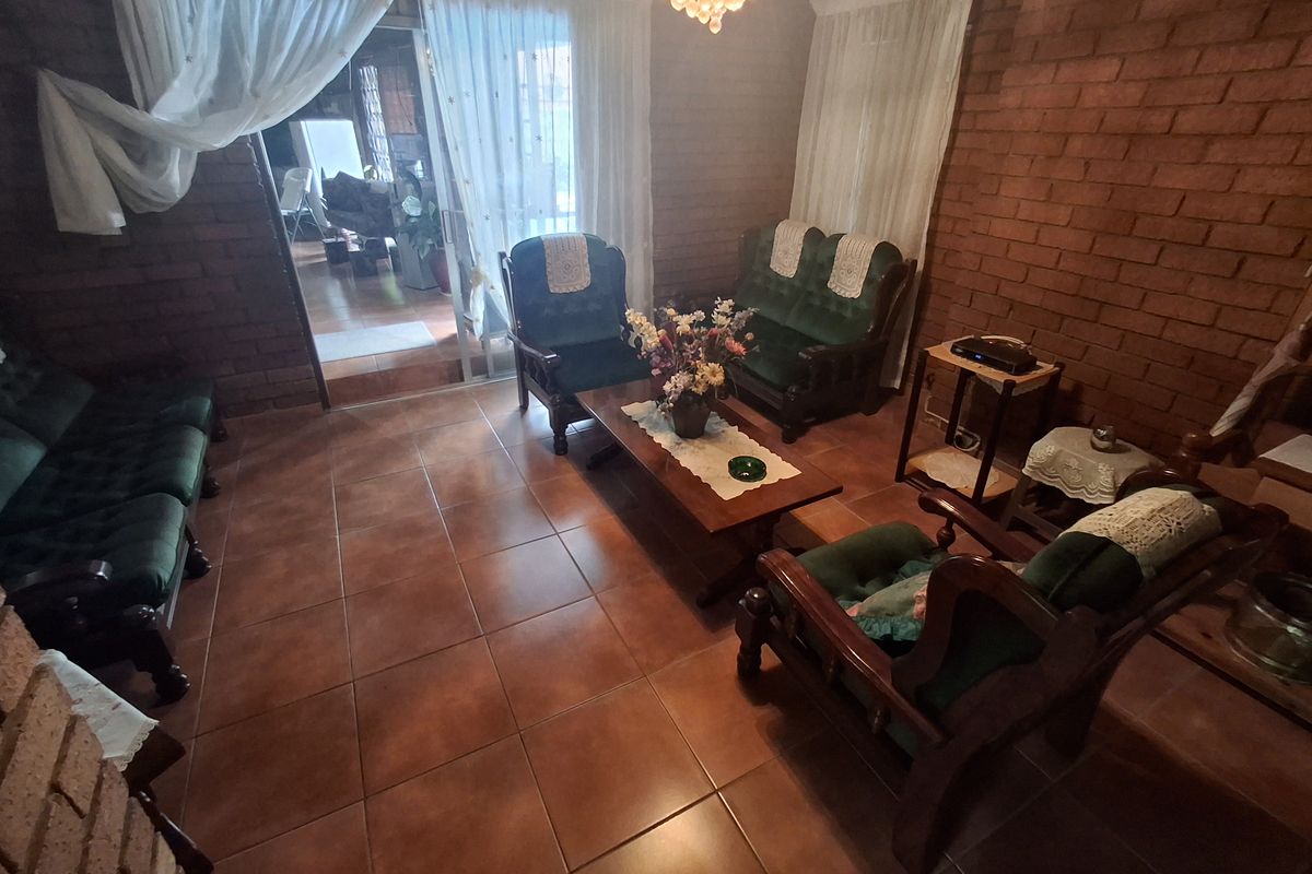 A living room featuring exposed brick walls, ceramic tile flooring, and a sliding glass door leading to an adjacent space.