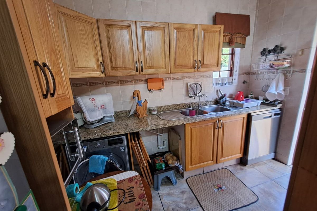 A functional kitchen featuring oak cabinetry, granite countertops, a double sink, and tiled finishes, offering a practical layout for daily use.
