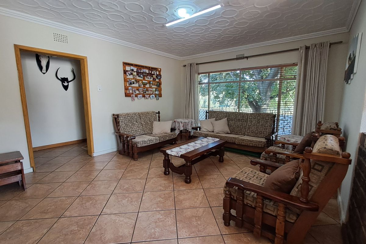 A spacious living room featuring tiled flooring, a textured ceiling, and a brick fireplace surround, offering a comfortable and functional living space.