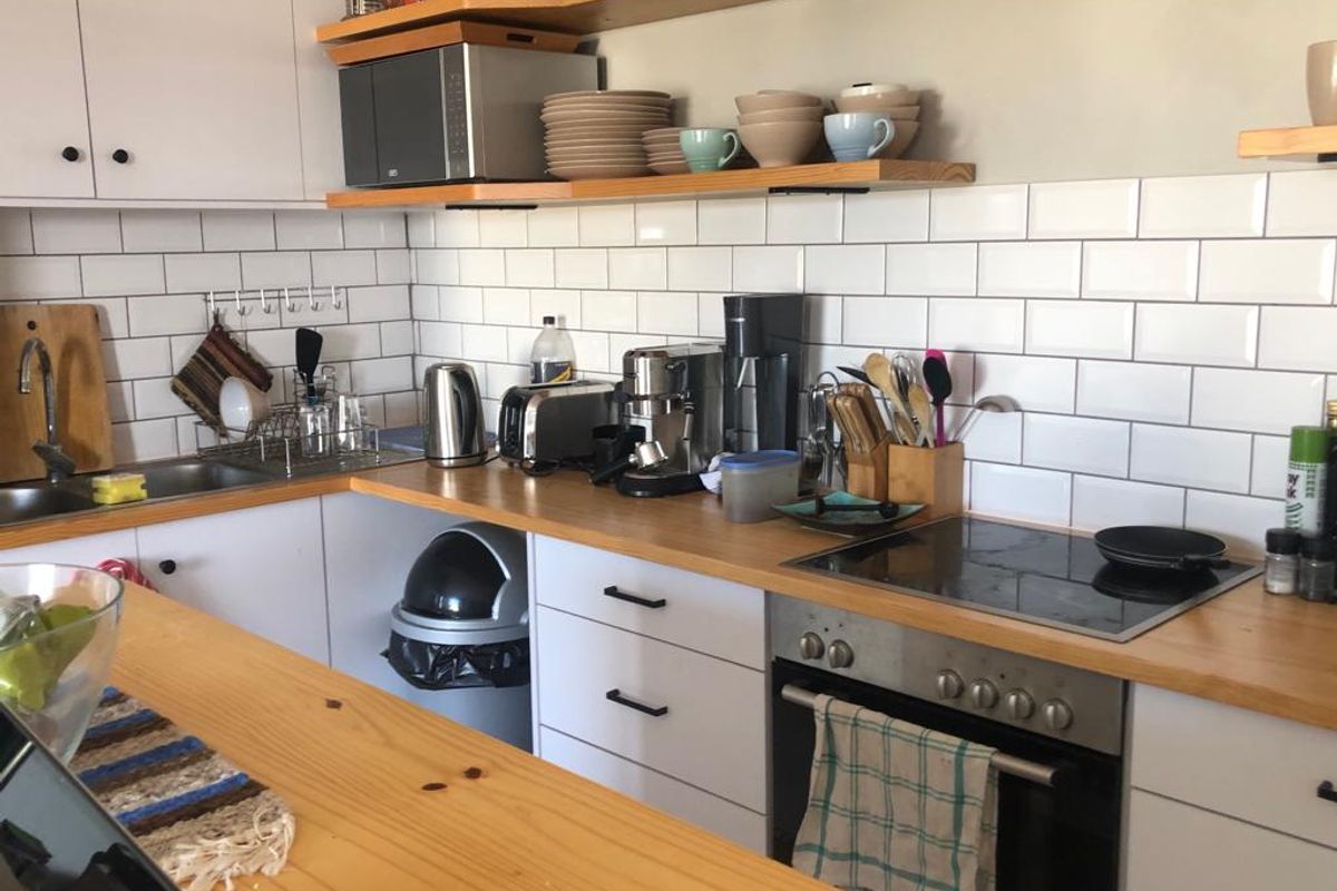 A functional kitchen featuring white cabinetry, wooden countertops, a subway tile backsplash, and integrated cooking appliances.