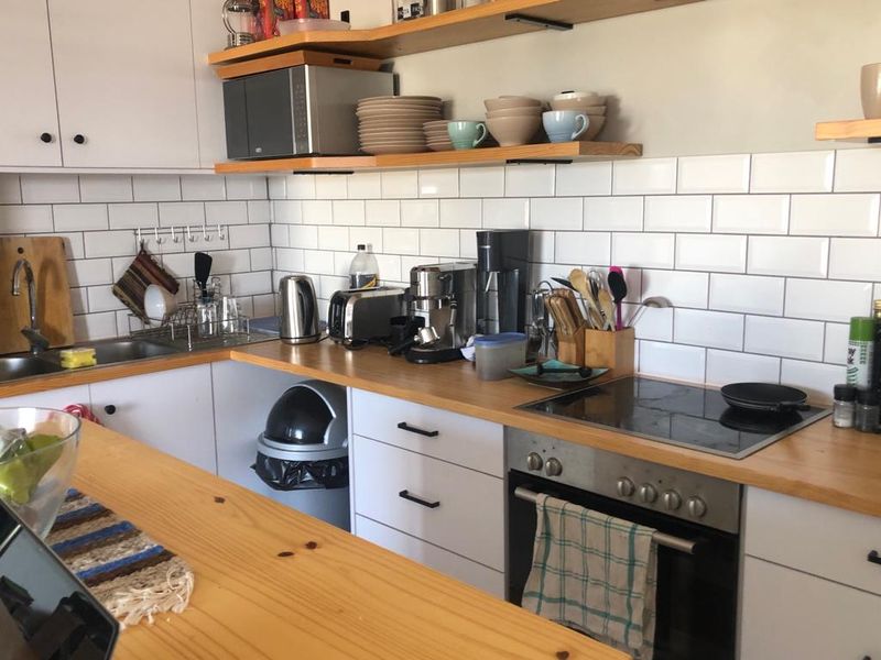 A functional kitchen featuring white cabinetry, wooden countertops, a subway tile backsplash, and integrated cooking appliances.