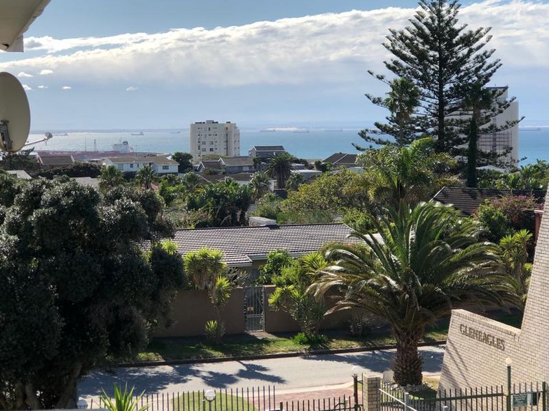 A scenic elevated view overlooking the surrounding neighborhood, lush greenery, and the distant ocean coastline.