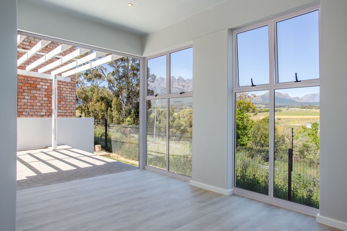 Bright living area featuring large windows with scenic mountain views and seamless access to an outdoor patio with a pergola.