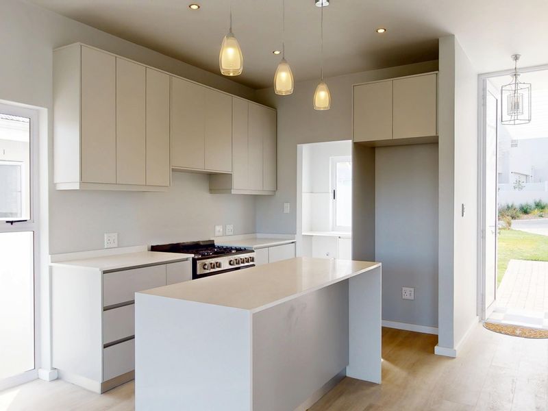 Modern kitchen featuring a central island, stone countertops, built-in cabinetry, and a gas stove, with direct access to the outdoor area.
