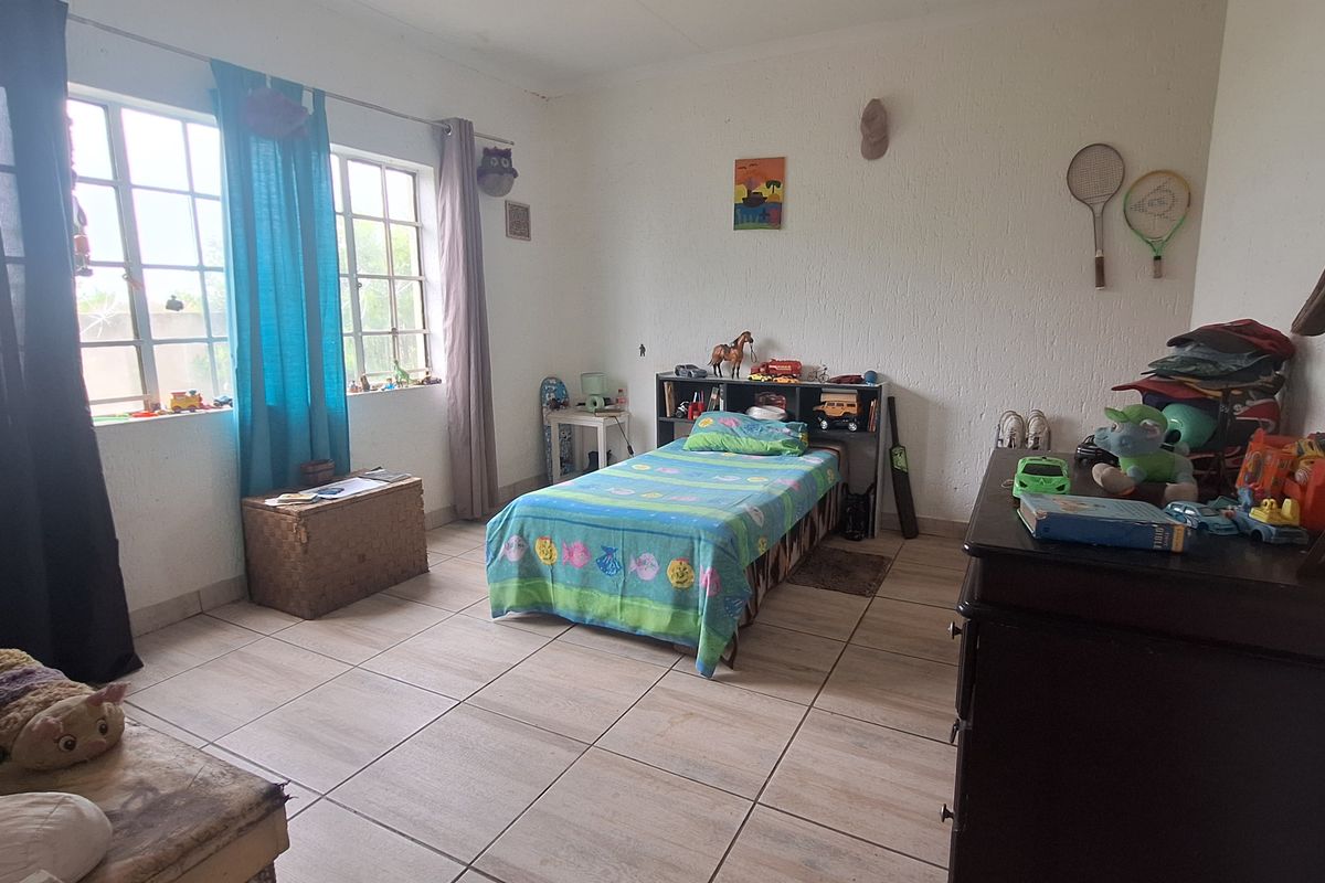 A bedroom featuring tiled flooring and large windows that provide natural light.