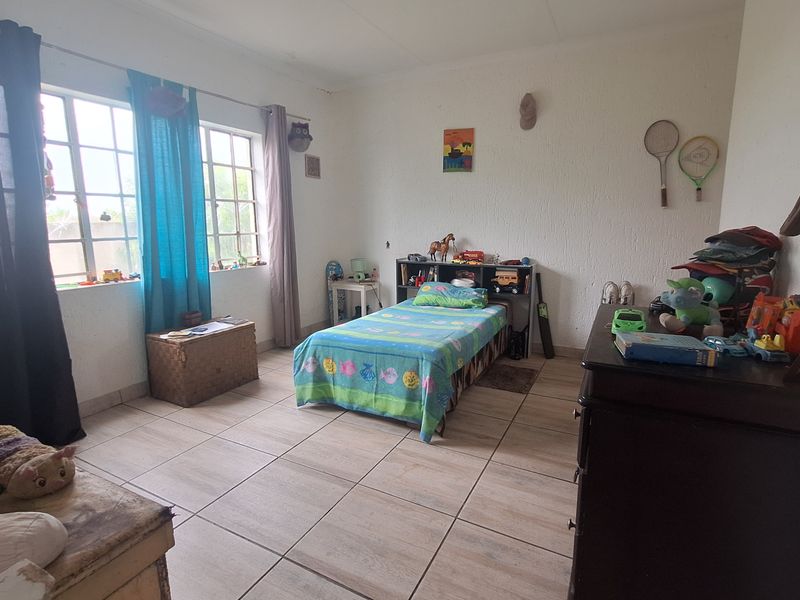 A bedroom featuring tiled flooring and large windows that provide natural light.