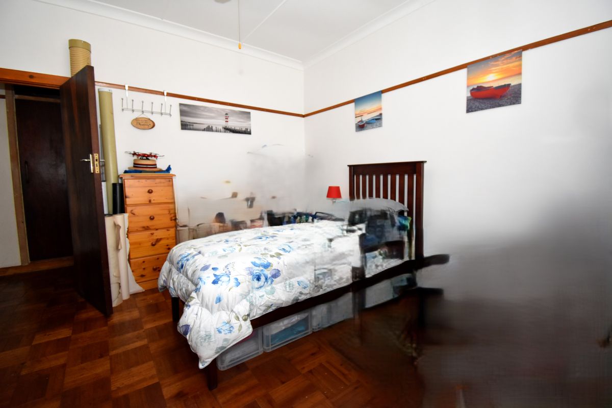 A bedroom featuring parquet timber flooring, picture rails, and a standard door entrance.