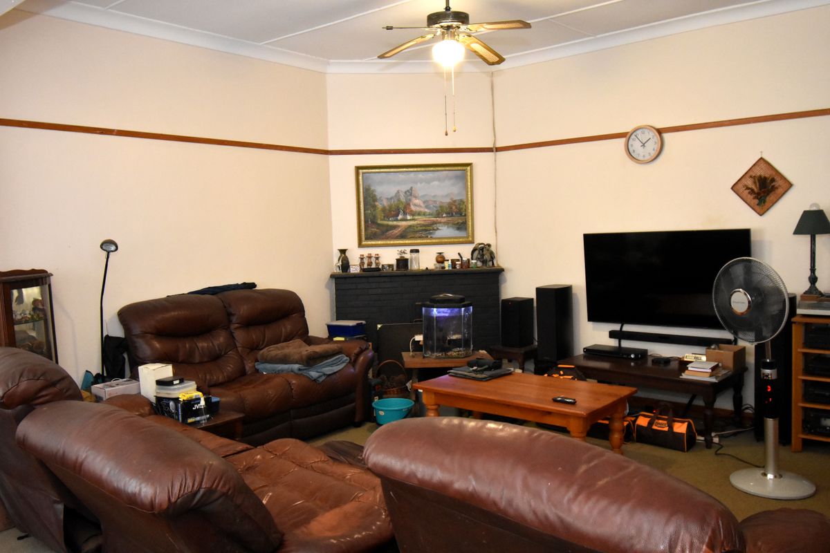 A living room featuring a painted brick fireplace, ceiling fan, and picture rail detailing.