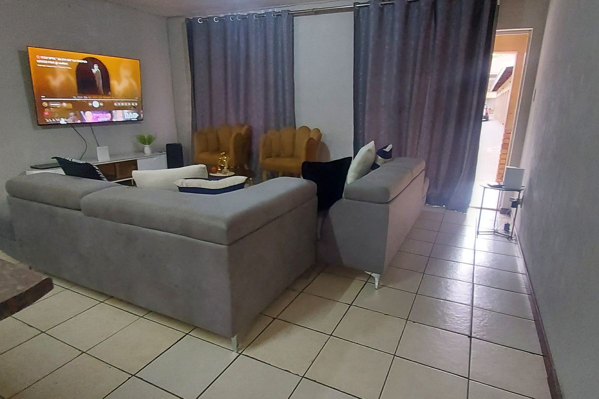 A living room area featuring tiled flooring and a sliding door leading to an outdoor space.