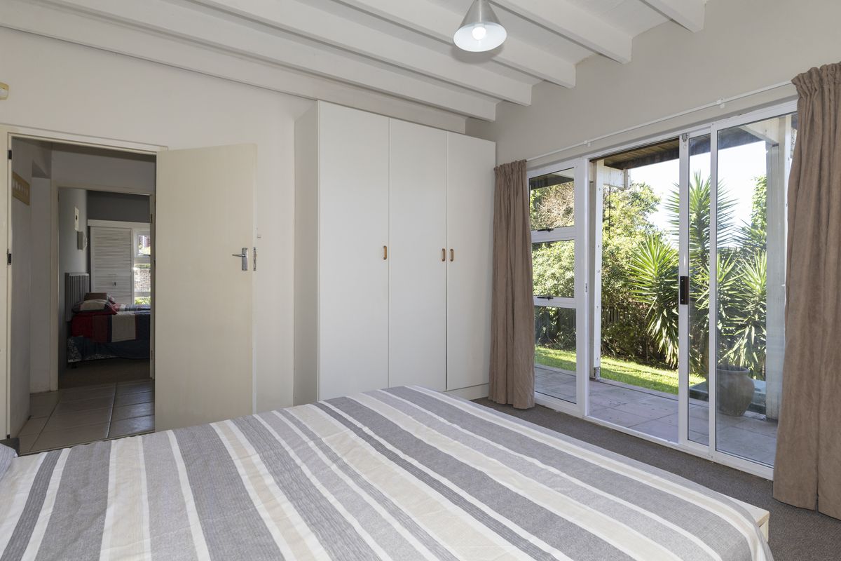 Bedroom featuring built-in wardrobes, exposed beam ceiling, and sliding glass doors providing direct access to the garden patio.