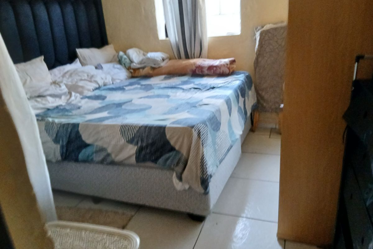 A bedroom featuring tiled flooring and a window, providing a functional space for rest.