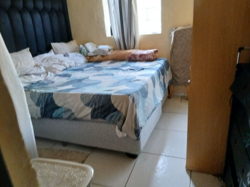 A bedroom featuring tiled flooring and a window, providing a functional space for rest.