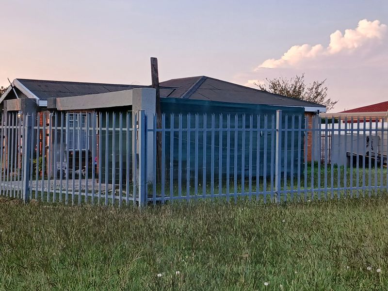 Front view of a residential property featuring steel palisade fencing and a pitched roof structure.