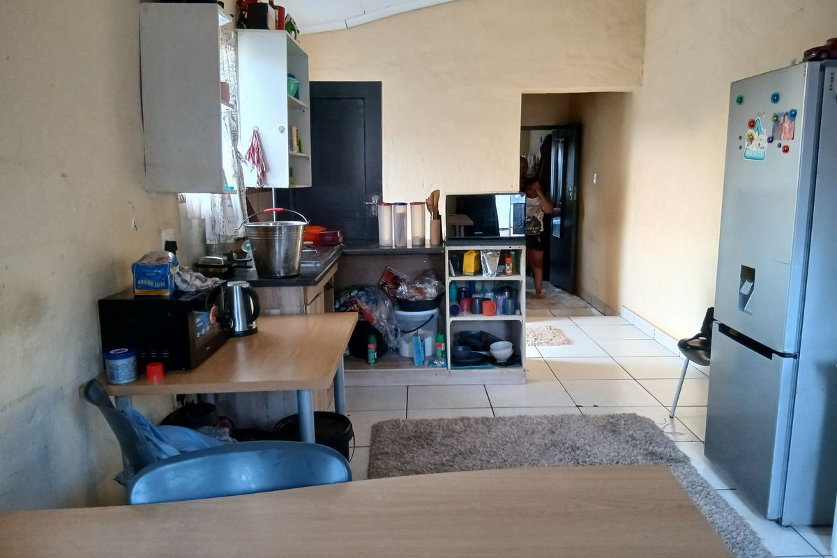 A functional kitchen area featuring tiled flooring and basic built-in cabinetry, offering a practical layout with potential for cosmetic updates.