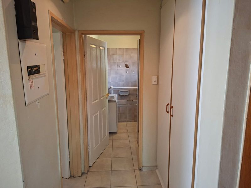 A functional hallway featuring built-in storage cupboards, tiled flooring, and direct access to an adjacent bathroom area.