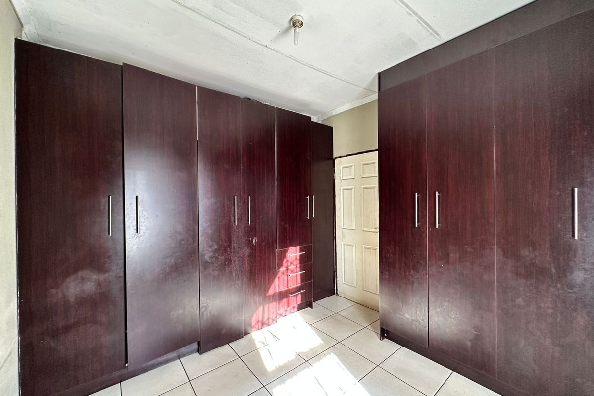 A bedroom featuring extensive built-in dark wood cabinetry with ample storage space and tiled flooring.
