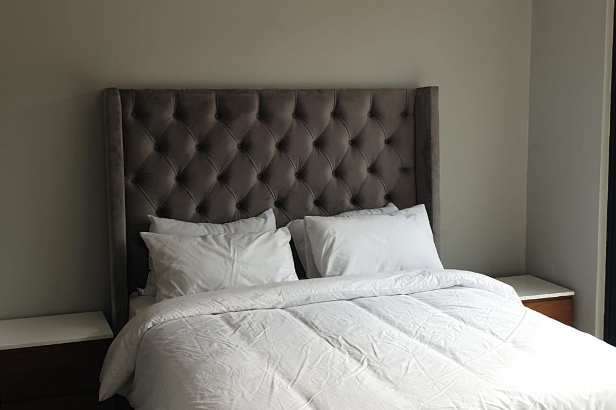 A well-maintained bedroom featuring neutral wall tones, tiled flooring, and a wall-mounted split-system air conditioning unit for climate control.