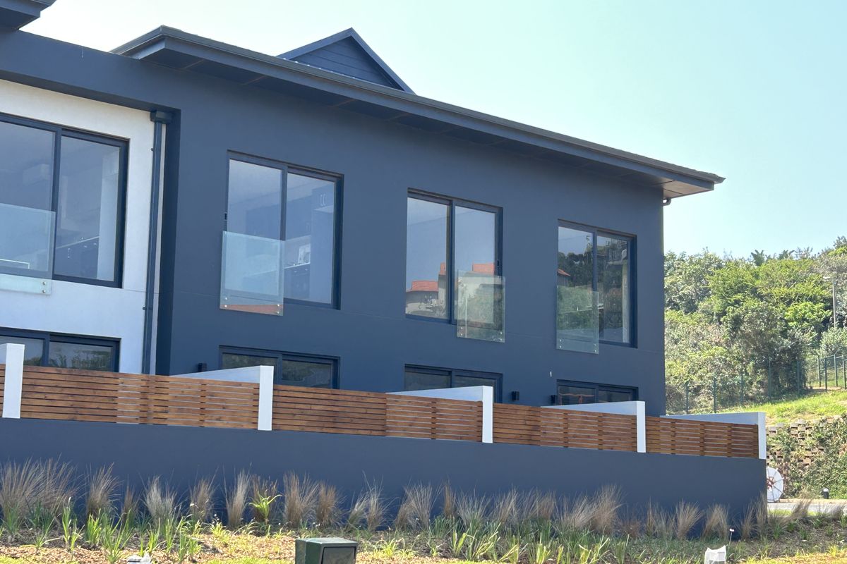 A modern apartment exterior featuring dark-toned facade, glass balustrades, and timber privacy screens, showcasing contemporary architectural design and clean lines.