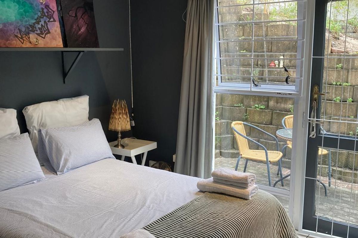 A bedroom featuring tiled flooring and direct access to a private outdoor patio area through a glass door with security bars.