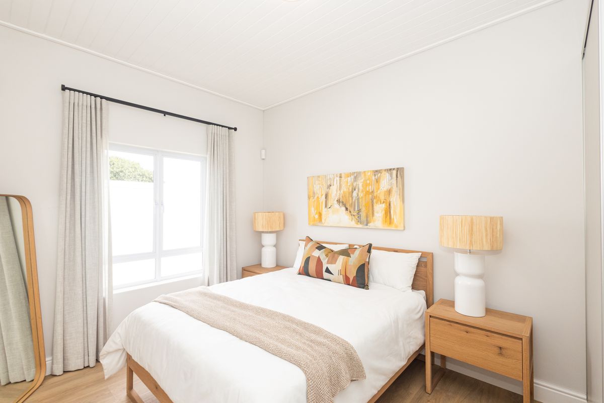 A bright and well-maintained bedroom featuring timber flooring, a classic tongue and groove ceiling, and a built-in wardrobe.
