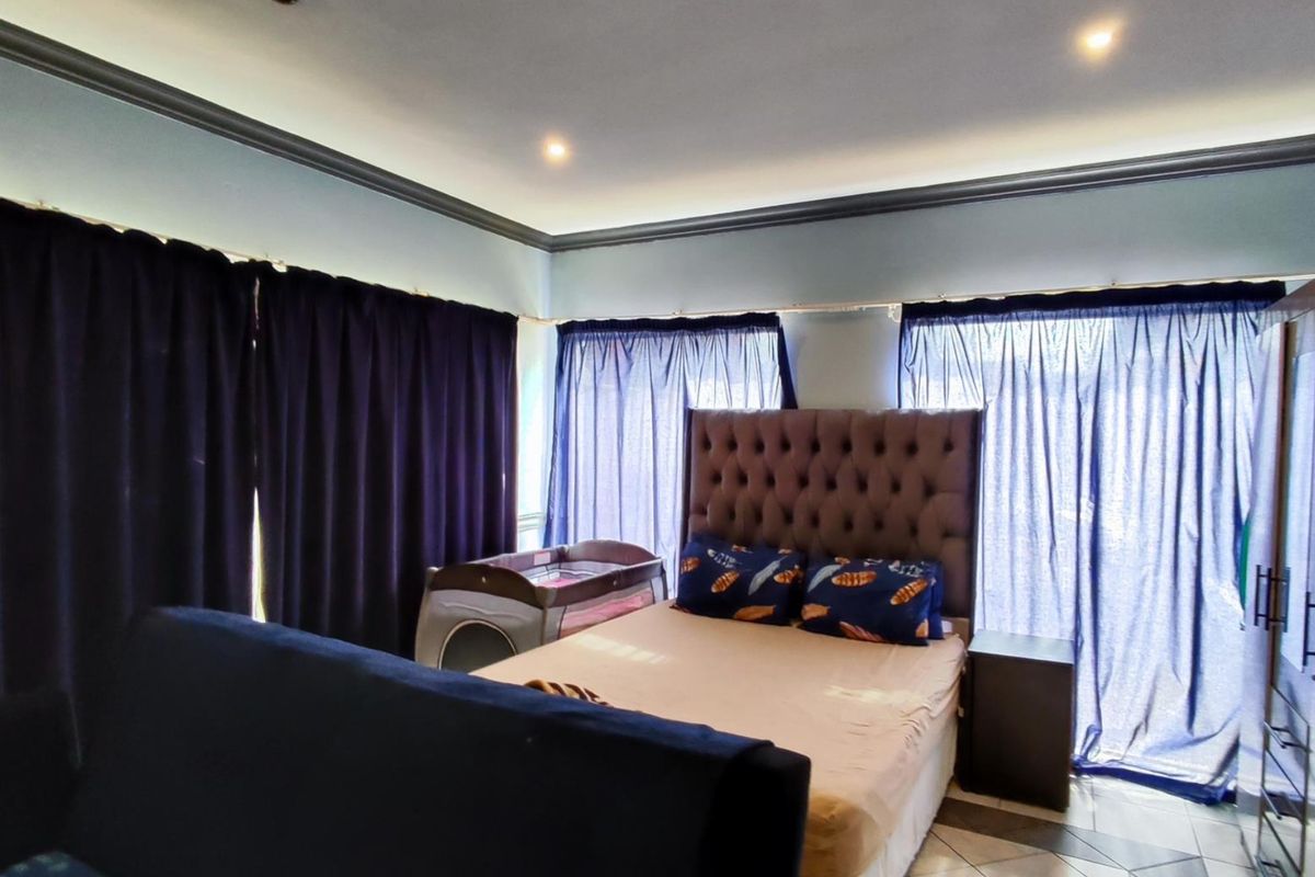 A bedroom featuring tiled flooring, crown molding, and recessed downlighting, providing a functional space with natural light access.
