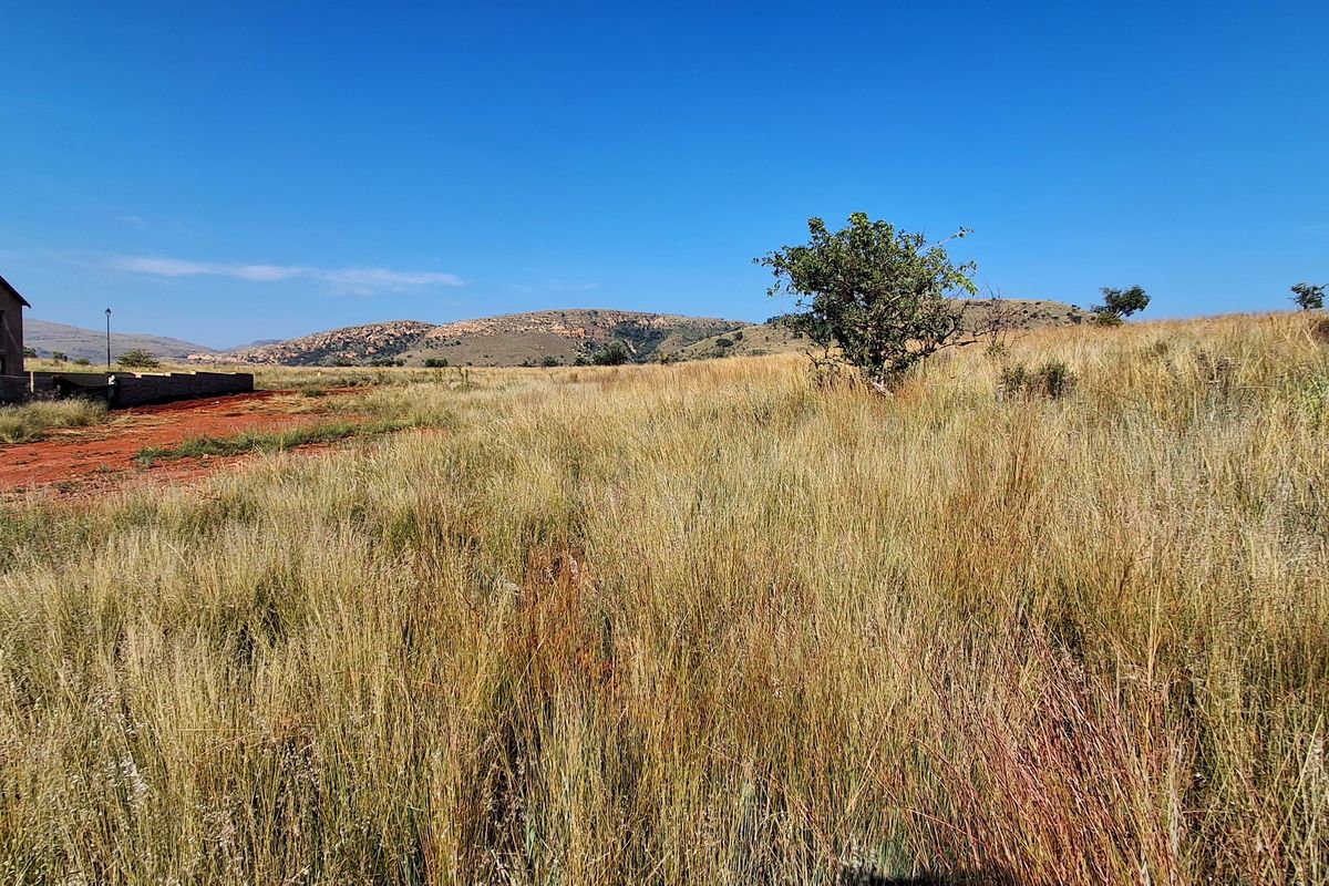 A wide-angle view of the vacant residential land featuring natural grassland and distant mountain scenery.