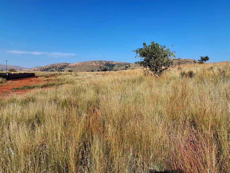 A wide-angle view of the vacant residential land featuring natural grassland and distant mountain scenery.