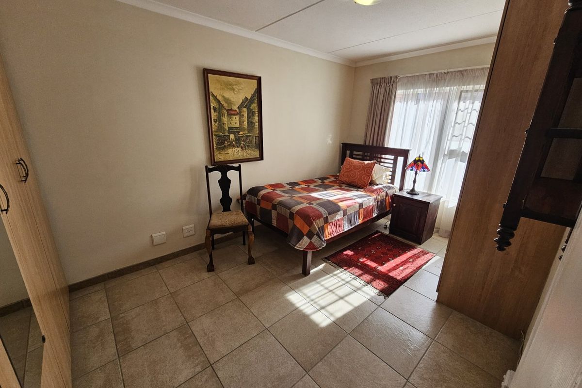 A bedroom featuring tiled flooring, built-in cupboards, and natural light from a window with curtain tracks.