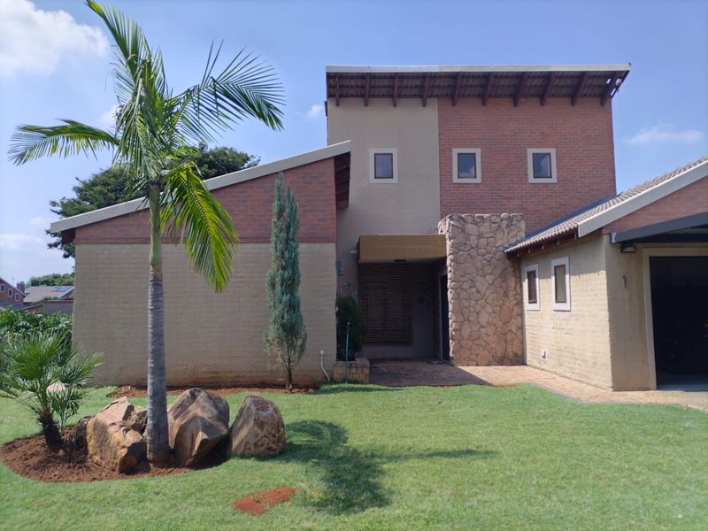 Front elevation of a modern house featuring a combination of brick and stone cladding, a paved driveway, and an integrated garage.