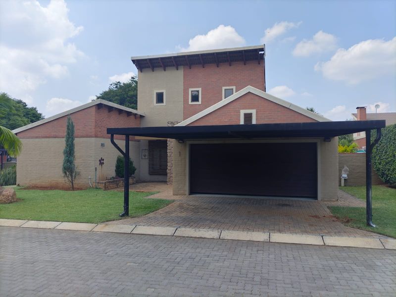 Front elevation of a modern brick house featuring a paved driveway, integrated garage, and a covered carport area.