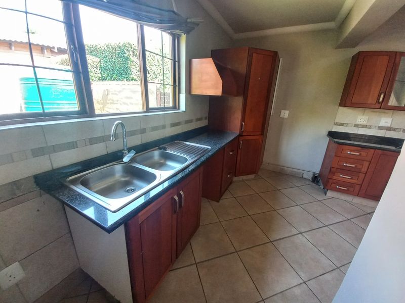 A functional kitchen featuring wooden cabinetry, granite countertops, a double bowl sink, and tiled flooring, offering a solid foundation for modern updates.