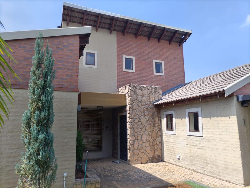 Front elevation of a multi-level house featuring a combination of brick and stone cladding with a covered entrance and paved driveway.
