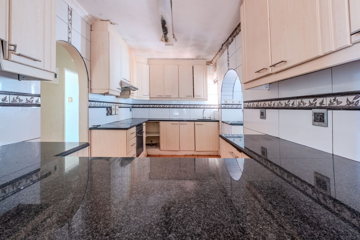 A dated kitchen featuring granite countertops, built-in cabinetry, and an integrated oven, currently requiring ceiling repairs and cosmetic updates.