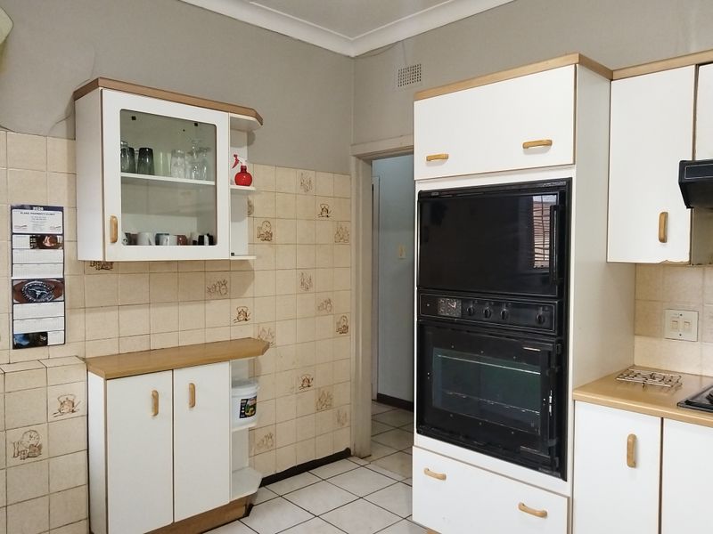 A functional kitchen featuring built-in cabinetry, a double oven, and tiled finishes, offering a dated aesthetic ready for modern updates.