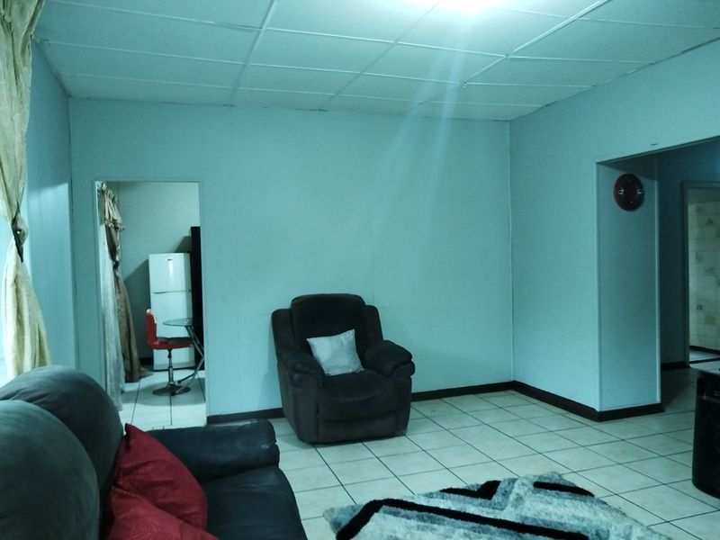 A living room area featuring tiled flooring and a drop ceiling, providing a basic foundation for potential interior updates.