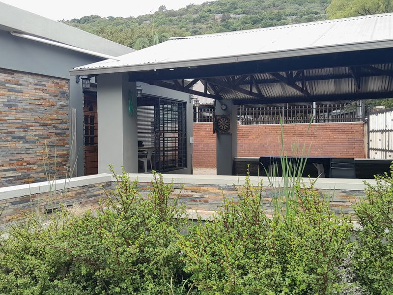A well-maintained covered outdoor patio area featuring stone cladding, a corrugated metal roof, and a built-in counter, perfect for outdoor entertaining.