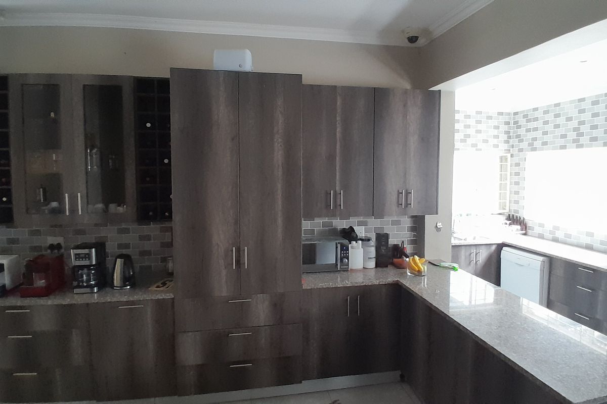 Modern kitchen featuring dark wood cabinetry, granite countertops, a subway tile backsplash, and integrated appliances with a dedicated wine storage section.