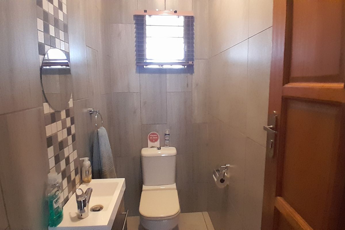 A compact bathroom featuring modern tiled walls, a wall-mounted basin, and a standard toilet.
