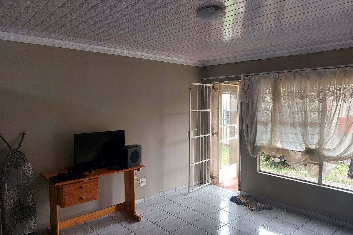 A living area featuring tiled flooring, a security gate, and a large window providing natural light and garden access.