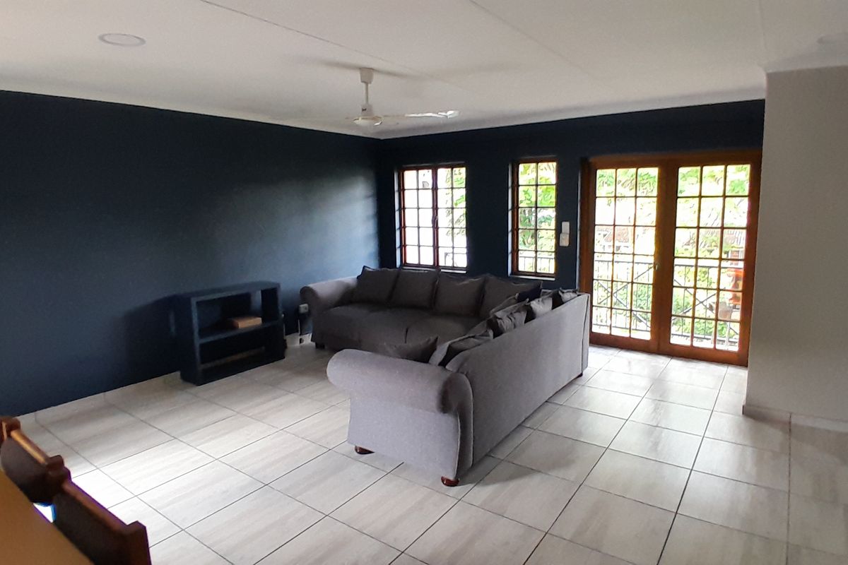 Spacious living room featuring tiled flooring, recessed lighting, a ceiling fan, and large french doors providing natural light and access to the outdoors.