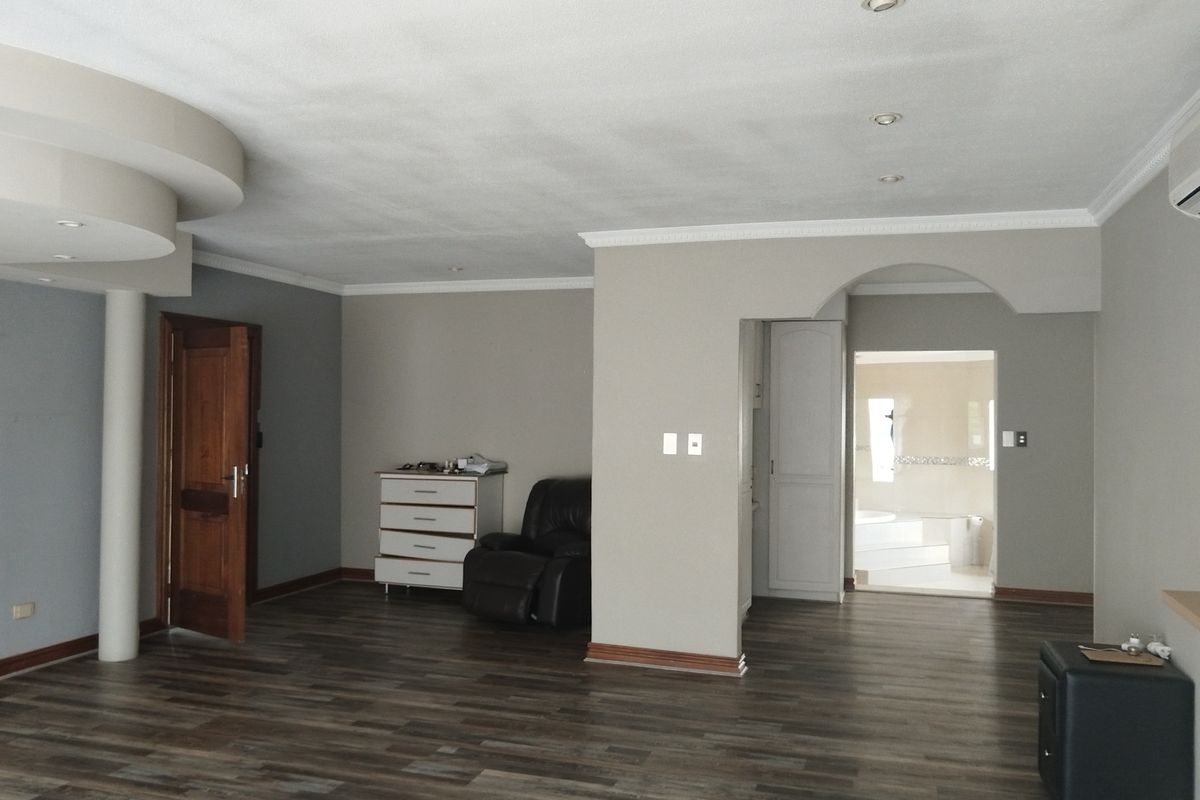 Spacious living area featuring laminate flooring, recessed ceiling lights, decorative crown molding, and an architectural archway leading to an adjacent room.