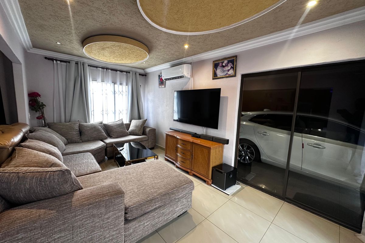 A comfortable living room featuring tiled flooring, a decorative recessed ceiling with circular accents, and a split-system air conditioner.
